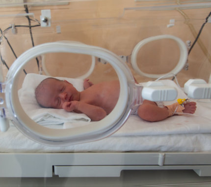 a baby lying in a hospital bed receiving medical attention from a healthcare